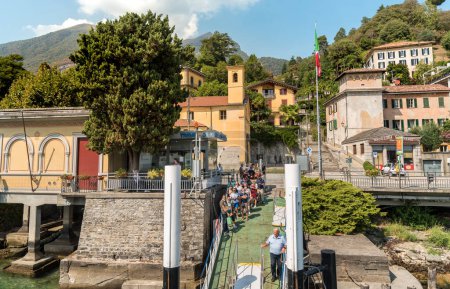 Photo for Tremezzo, Lombardy, Italy - September 5, 2022: The pier of the village Tremezzo with tourists are waiting for the ferry boat for sightseeing on Lake Como. - Royalty Free Image