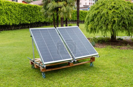 Foto de Paneles fotovoltaicos mojados por la lluvia en la plataforma de madera en el jardín del hogar. Concepto de energía verde. - Imagen libre de derechos