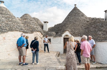 Photo for Alberobello, Puglia, Italy - October 5, 2023: Tourists visiting trulli limestone houses in the ancient village Alberobello, in province of Bari. - Royalty Free Image