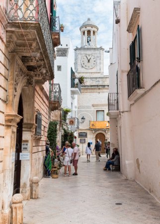 Photo for Locorotondo, Puglia, Italy - October 5, 2023: Narrow street with a view of the Clock Tower in the center of Locorotondo, metropolitan city of Bari. - Royalty Free Image