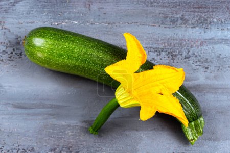Photo for Close-up of a zucchini with the flower-Top view on old gray board. - Royalty Free Image