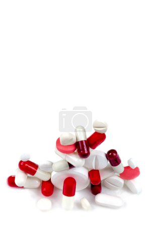 Foto de Cápsulas y comprimidos rojos y blancos apilados sobre un fondo blanco. - Imagen libre de derechos