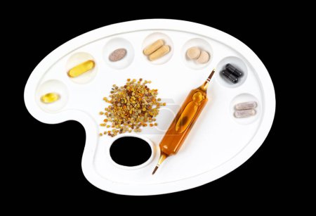 Foto de Suplementos dietéticos en una paleta sobre un fondo negro. - Imagen libre de derechos