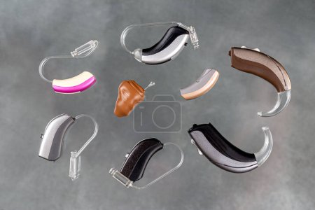 Photo for Presentation of a wide range of hearing aids seen from above on a gray background. - Royalty Free Image