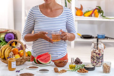 Photo for Woman , cut face a cup of tea in her hand, surrounded by cereals, fresh fruits and dried fruits, honey, - Royalty Free Image