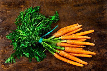Photo for Bunch of carrots close-up top view on old wooden background - Royalty Free Image