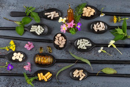 Kapseln und Pillen von Nahrungsergänzungsmitteln umgeben von Blumen und Heilpflanzen-Top view.
