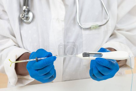 Médecin tenant un stérilet hormonal complet prêt à être placé sur une patiente.