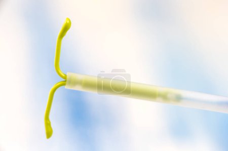 Hormonal IUD in horizontal close-up on a light bluish background.