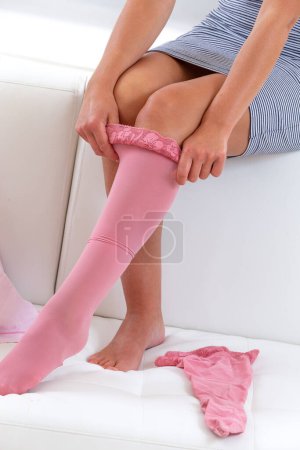 Woman putting on pink compression stockings