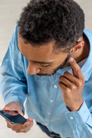 Young man adjusting the volume intensity of the hearind aid with the smartphone.