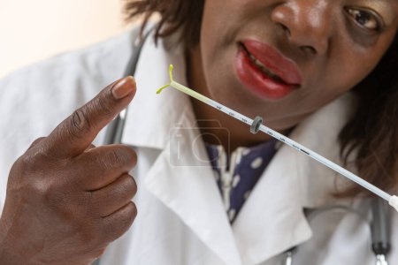 Afrikanische Ärztin spricht mit einer Patientin, während sie die IUD zeigt.