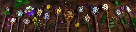 Panoramic of dietary supplements surrounded by medicinal plants on an old wooden board.