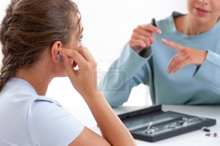 Foto de Mujer frente a un profesional de la audición probando un audífono. - Imagen libre de derechos