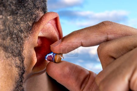 Photo for Close-up on the positioning of a digital hearing aid in a young man. - Royalty Free Image