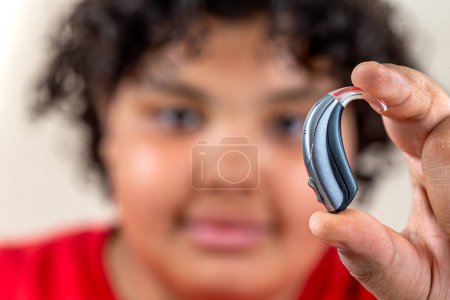Photo for 14 year old boy holding a hearing aid. - Royalty Free Image