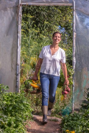 Mujer joven con pasos de alerta en el invernadero con una cesta llena de verduras
