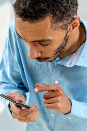 Photo for Young man adjusting the volume intensity of the hearing aid with the smartphone. - Royalty Free Image