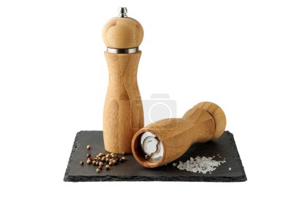Photo for Wooden salt and peppers mill on black slate board isolated on white background. Two bamboo spice grinders. - Royalty Free Image