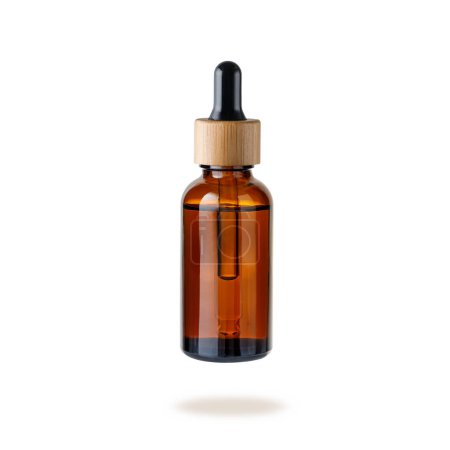 Glass dropper bottle with cap of bamboo wood for face serum or essential oil or pharmaceutical tincture. Glass and wooden bottle flying isolated on white background. Zero waste concept.
