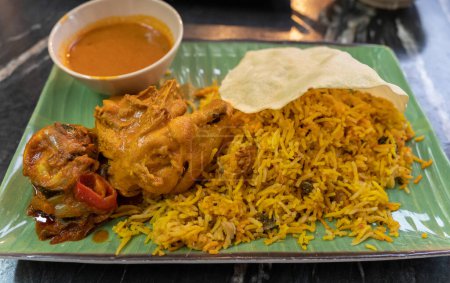 Vue rapprochée du riz biryani au poulet au curry et au papadam