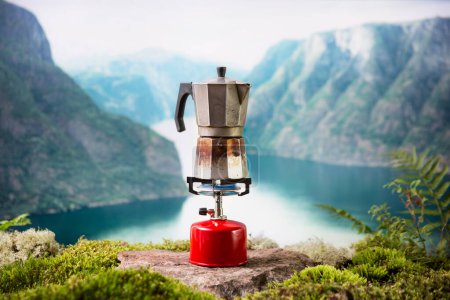 Cocinar, hacer café o té en un quemador portátil de gas de camping con un cilindro de gas rojo con un fondo de naturaleza escandinava. Senderismo de verano, ecoturismo, supervivencia.