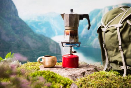 Kochen, Kaffee oder Tee kochen auf einem tragbaren Campinggasbrenner mit roter Gasflasche mit skandinavischem Hintergrund. Sommerwandern, Ökotourismus, Überleben.