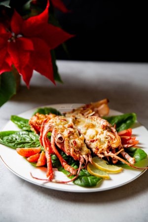 Grilled lobster with lemon and green leaves on a white plate. Delicious lobster Thermidor served on porcelain plate