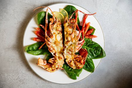 Grilled lobster with lemon and green leaves on a white plate. Delicious lobster Thermidor served on porcelain plate