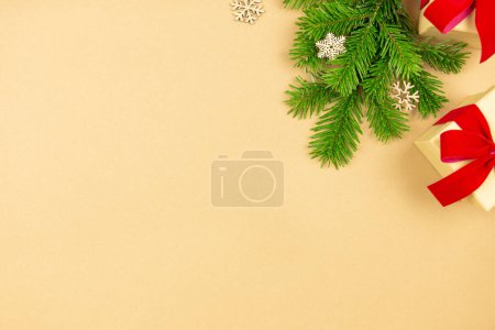Piso de Navidad con cajas de regalo y decoración de cinta roja, ramas de árbol de Navidad sobre fondo de papel artesanal. Composición de maqueta estilo festivo. Vista superior. Copiar espacio. 