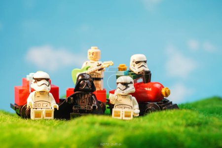 Photo for Bangkok, Thailand - October 3, 2022: Star Wars Lego Stormtroopers, Darth Vader and guitarist minifigures near red train against nature background. - Royalty Free Image