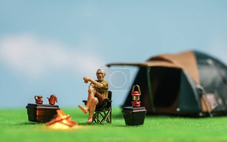 Téléchargez les photos : Figure humaine miniature d'un homme âgé assis près d'une tente et buvant du café à l'extérieur. Conception conceptuelle du camping. - en image libre de droit