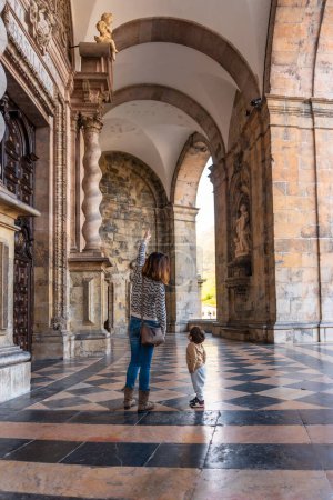 Photo for Mother and son at the door of the Sanctuary of Loyola pointing to sculptures, Baroque church of Azpeitia - Royalty Free Image
