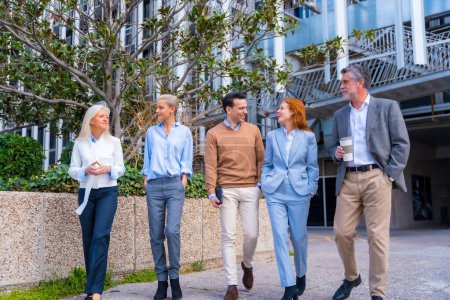 Photo for Group of coworkers walking outdoors in a corporate office area, businesswoman and businessman and executives in commercial area - Royalty Free Image
