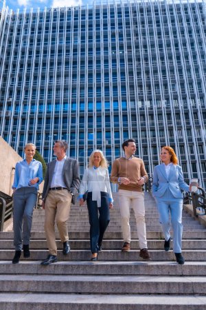 Photo for Cheerful group of coworkers outdoors in a corporate office area going down some stairs going to work - Royalty Free Image