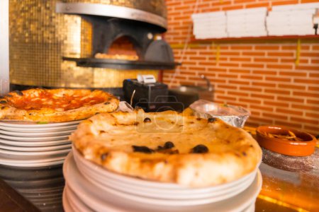 Téléchargez les photos : Four à pizza artisanal. Pizza fraîchement préparée sortant du four, pizza chaude - en image libre de droit