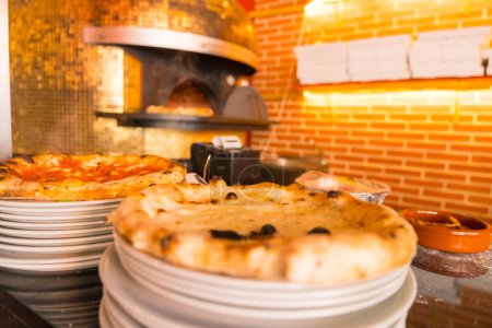 Téléchargez les photos : Four à pizza artisanal. Pizza fraîchement préparée sortant du four, pizza chaude et prête pour les clients - en image libre de droit