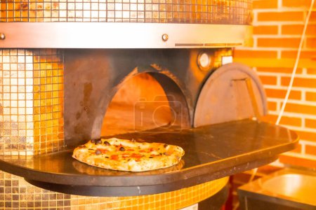 Téléchargez les photos : Four à pizza artisanal. Pizza fraîche sortie du four, pizza chaude et prête pour les clients - en image libre de droit