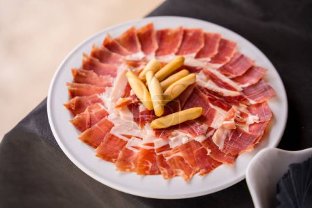 Dish with Iberico ham cut ready to eat. Ham cutter man. Service of a person cutting a piece of ham. traditional food of spain