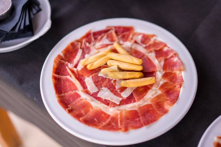 Photo for Dish with Iberico ham cut ready to eat. Ham cutter man. Service of a person cutting a piece of ham. traditional food of spain - Royalty Free Image