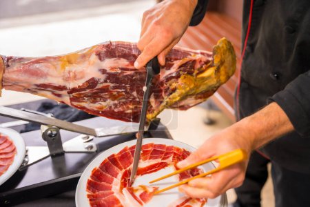 Photo for Ham cutter man. Service of a person cutting a piece of ham. Chef or cutter with a knife cutting slices. traditional food of spain - Royalty Free Image