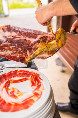 Photo for Iberian ham cutter man. Service of a person cutting a piece of ham. Chef or cutter with a knife cutting slices. traditional food of spain - Royalty Free Image