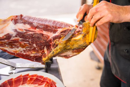Photo for Iberian ham cutter man. Service of a person cutting a piece of ham. Chef or cutter with a knife cutting slices. traditional food of spain - Royalty Free Image