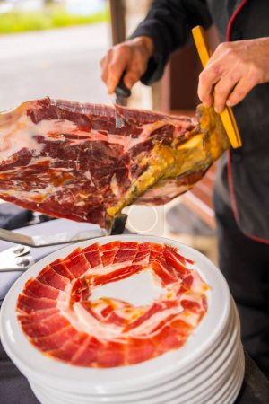 Photo for Iberian ham cutter man at a wedding. Service of a person cutting a piece of ham. Chef or cutter with a knife cutting slices. traditional food of spain - Royalty Free Image