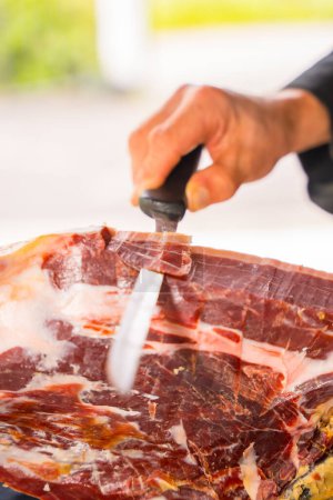 Photo for Detail of a man cutting Iberian ham at a wedding or event. Service of a person cutting a piece of ham. Cook or cutter with a knife. traditional food of spain - Royalty Free Image