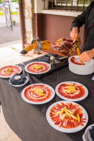 Photo for Detail of a man cutting Iberian ham at a wedding or event. Service of a person cutting a piece of ham. Cook or cutter with a knife. traditional food of spain - Royalty Free Image