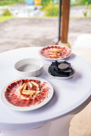 Photo for Dish with Iberico ham cut ready to eat. Ham cutter man. Service of a person cutting a piece of ham. traditional food of spain - Royalty Free Image