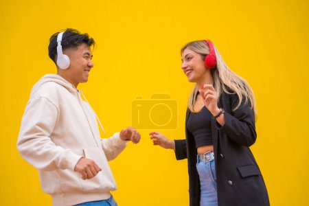 Multiethnic couple of Asian man and Caucasian woman on a yellow background, dancing bachata