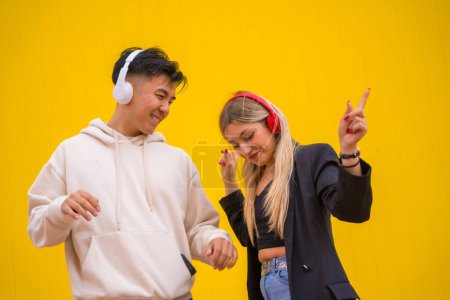 Multiethnic couple of Asian man and Caucasian woman on a yellow background, dancing bachata