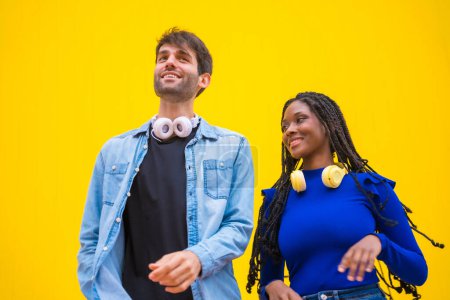 Multiethnic wedding couple of Caucasian man and woman of black ethnicity on a yellow background, dancing salsa and latin music